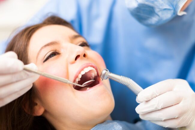 Frequently asked questions about cavities include what they are, how they form, and how they're treated. This image represents a woman getting dental treatment.